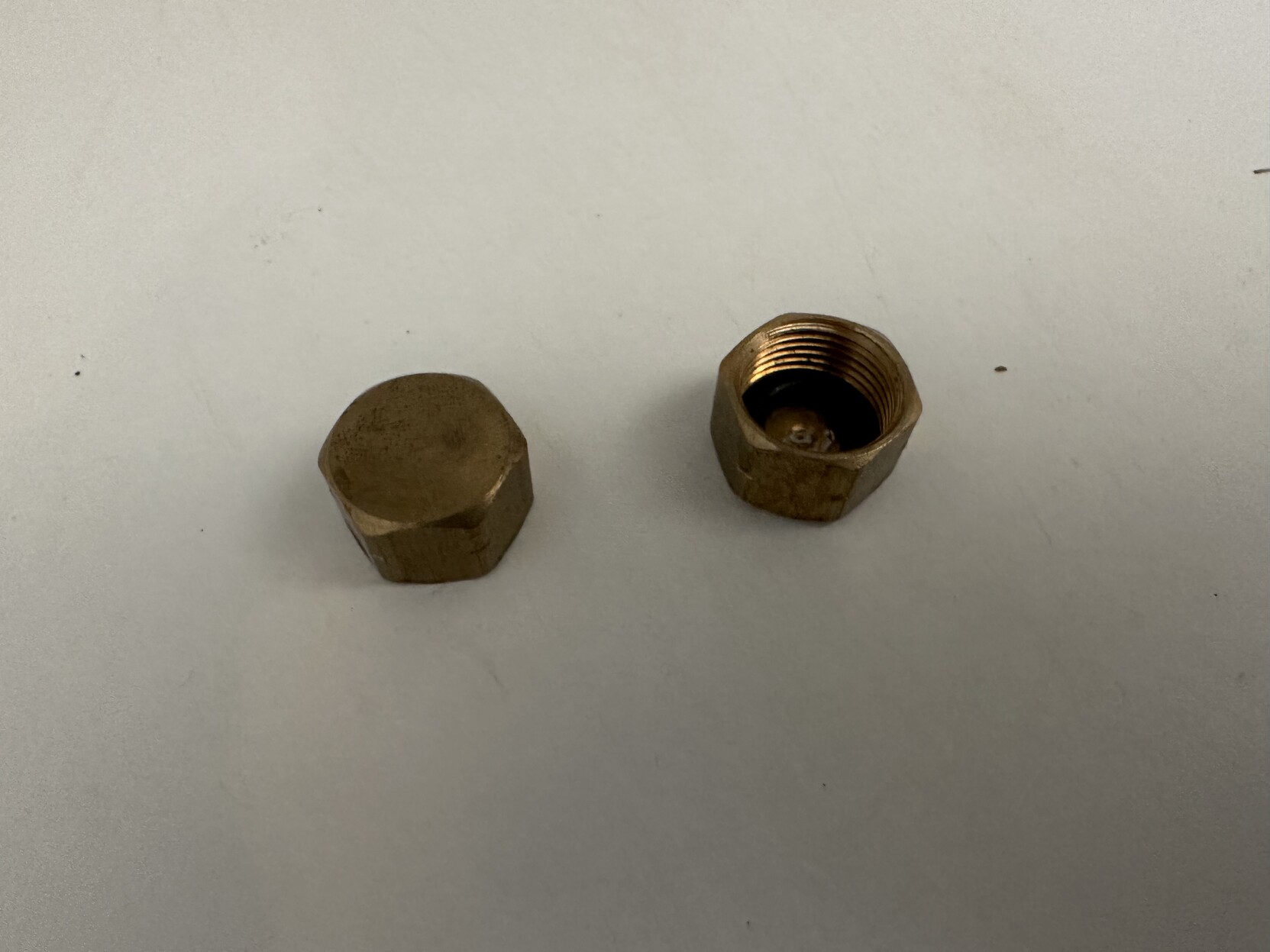 photo of small brass caps that fit onto water valves for faucets or toilets 