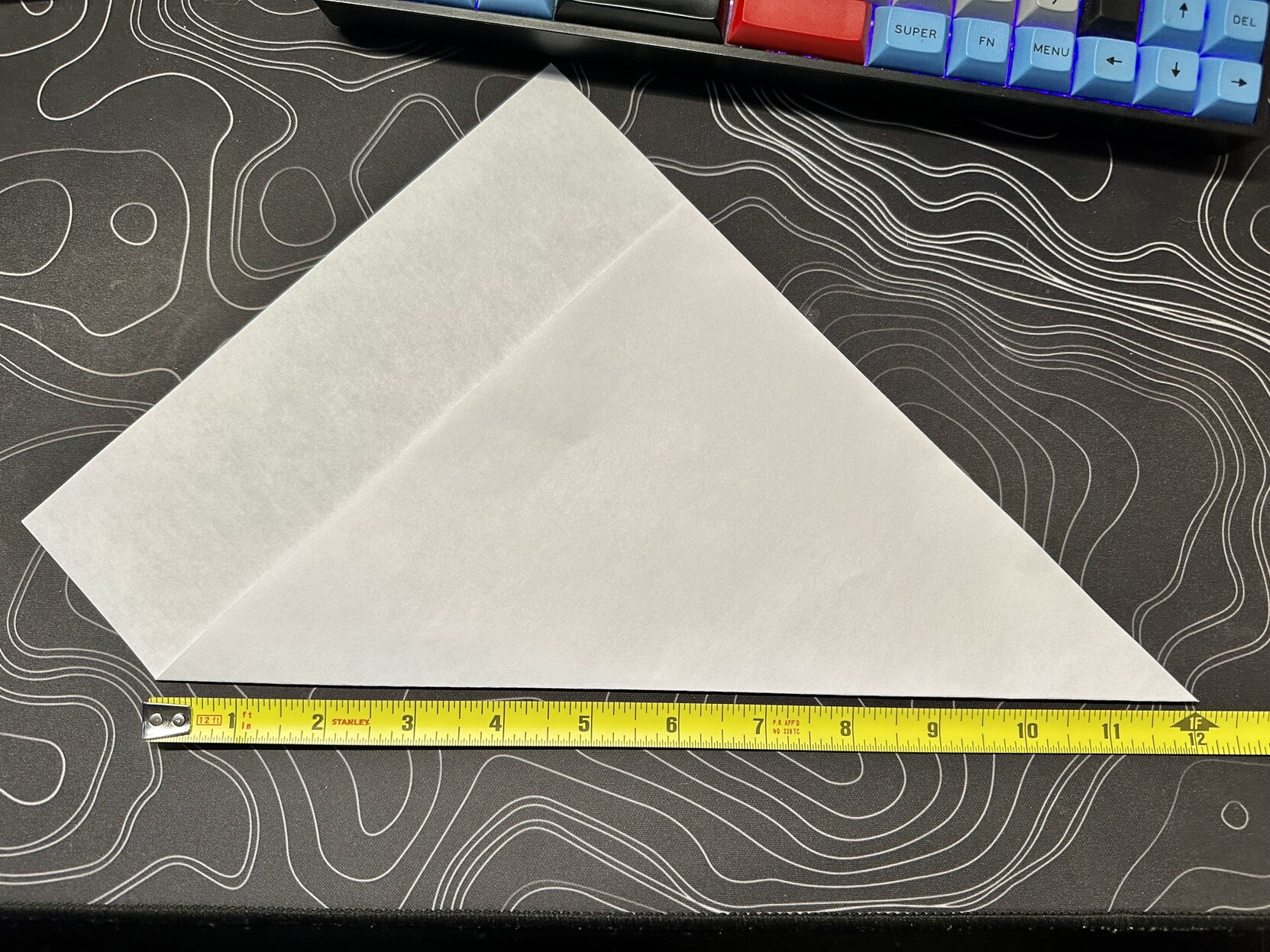 a photo demonstrating that a piece of 8-1/2” by 11” paper folded to make a triangle forms very nearly one foot on the hypotenuse 