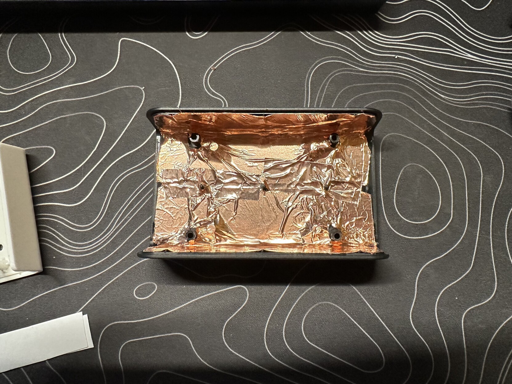 a photo of the bottom half of the mixer with shielding tape applied inside the case