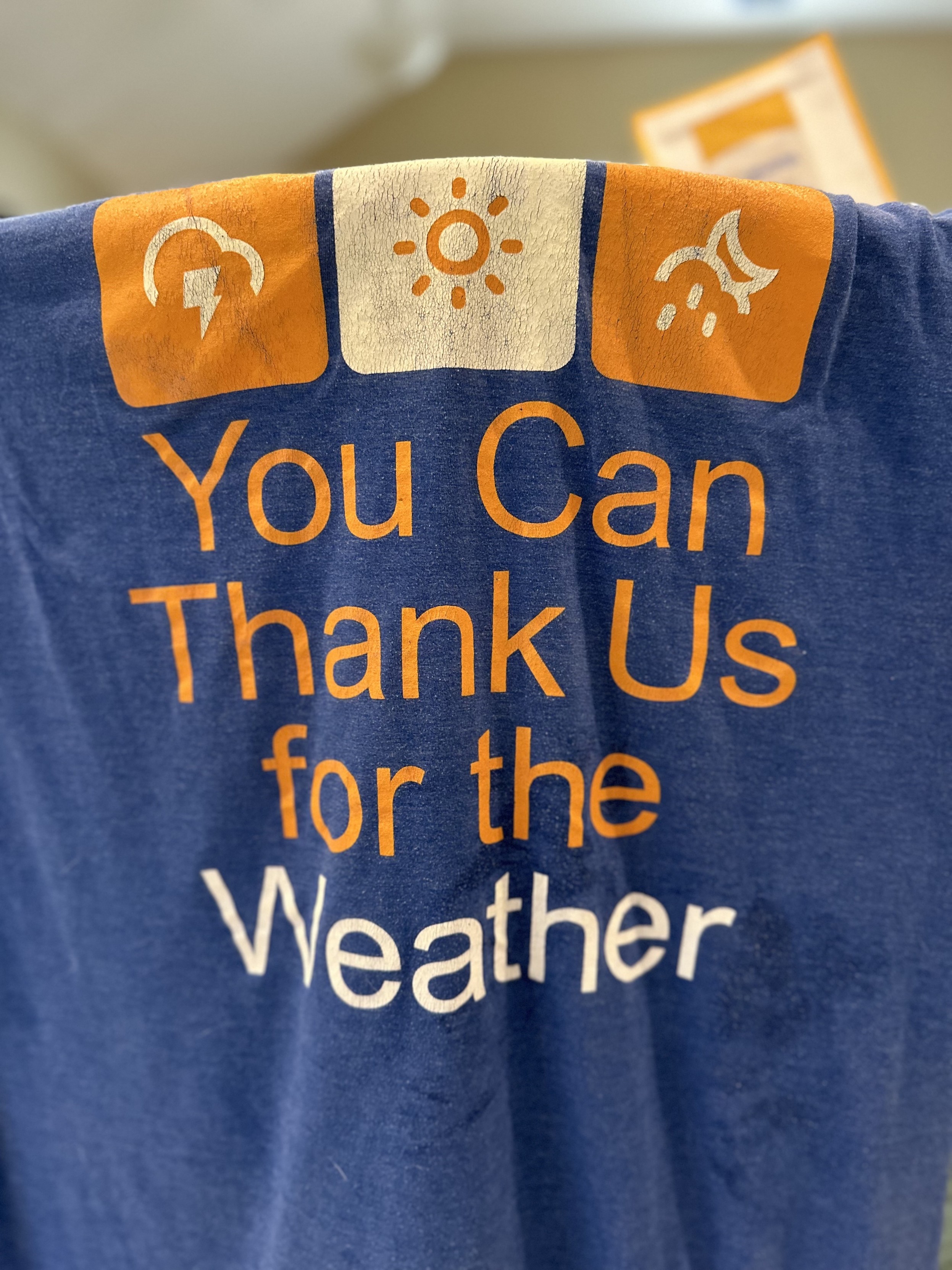 a photo of the back of a t-shirt that reads: “You Can Thank Us for the Weather”