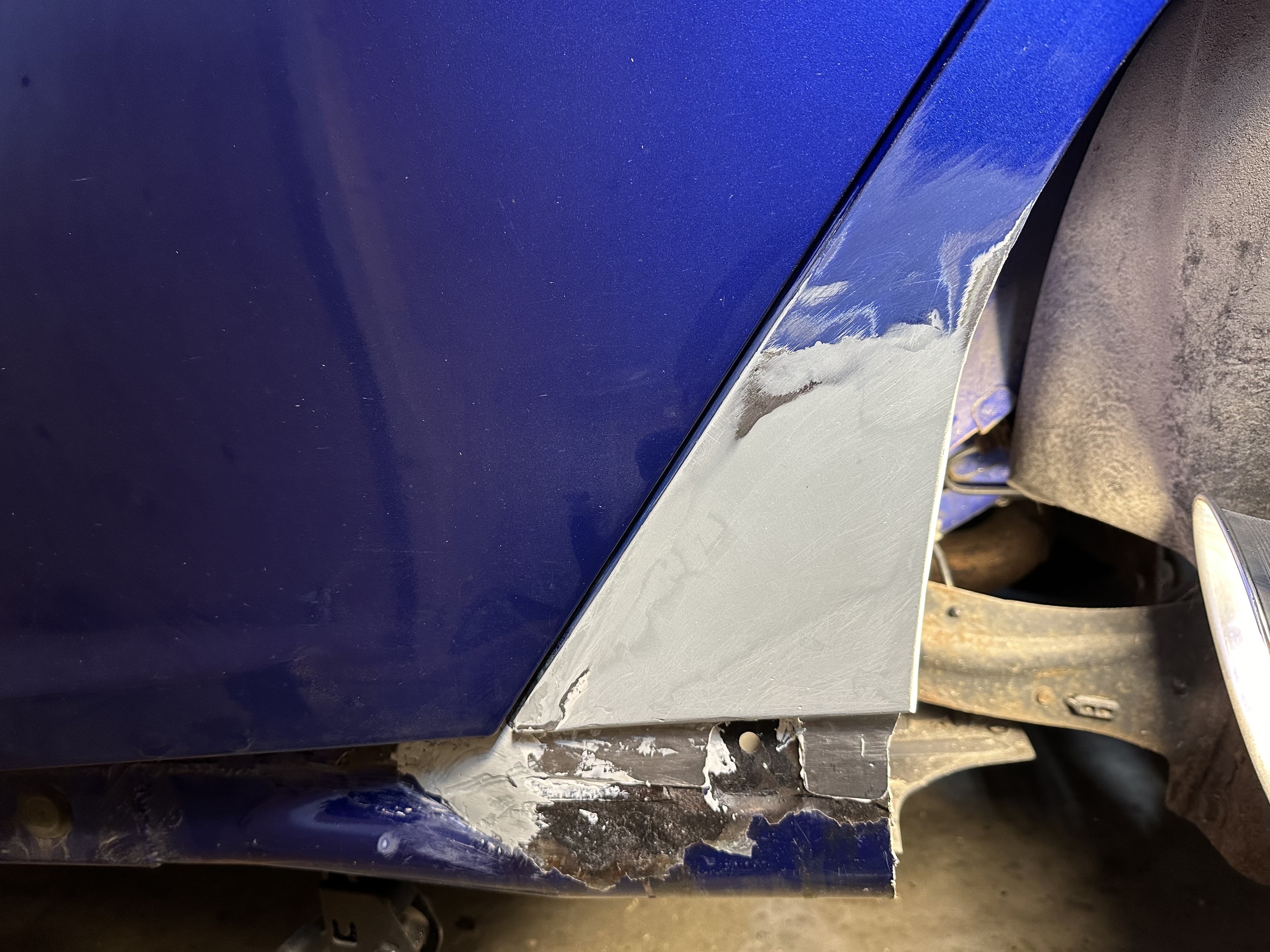 a photo of the lower quarter panel of my car with a patch panel glued in and bondo covering it to smooth out the repair