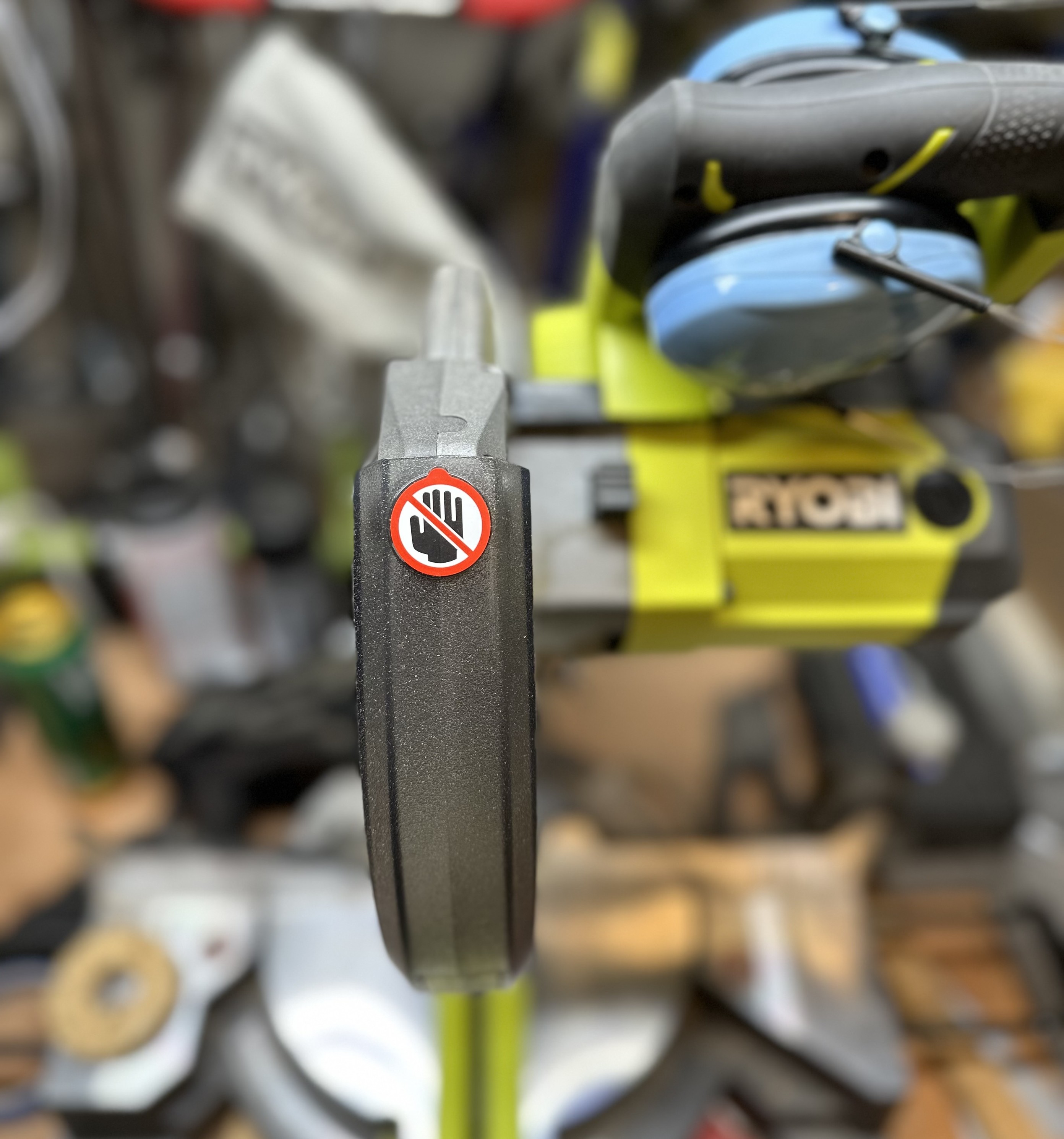 a photo of a sliding compound mitre saw with a sticker depicting a human hand, with a red circle and slash over it.