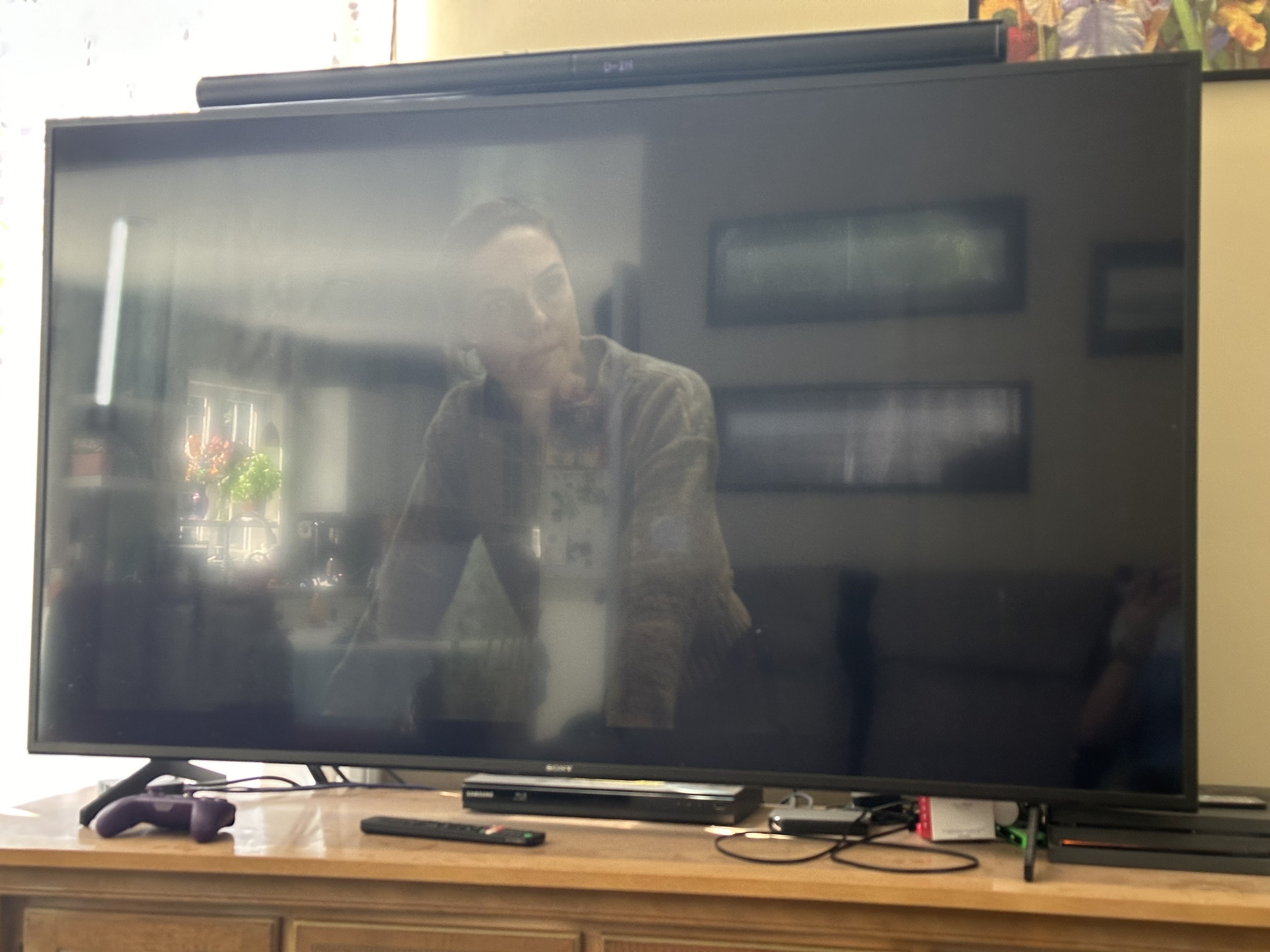 a photo of a television with an egregiously dark show on it, completely washed out with glare on the screen. 