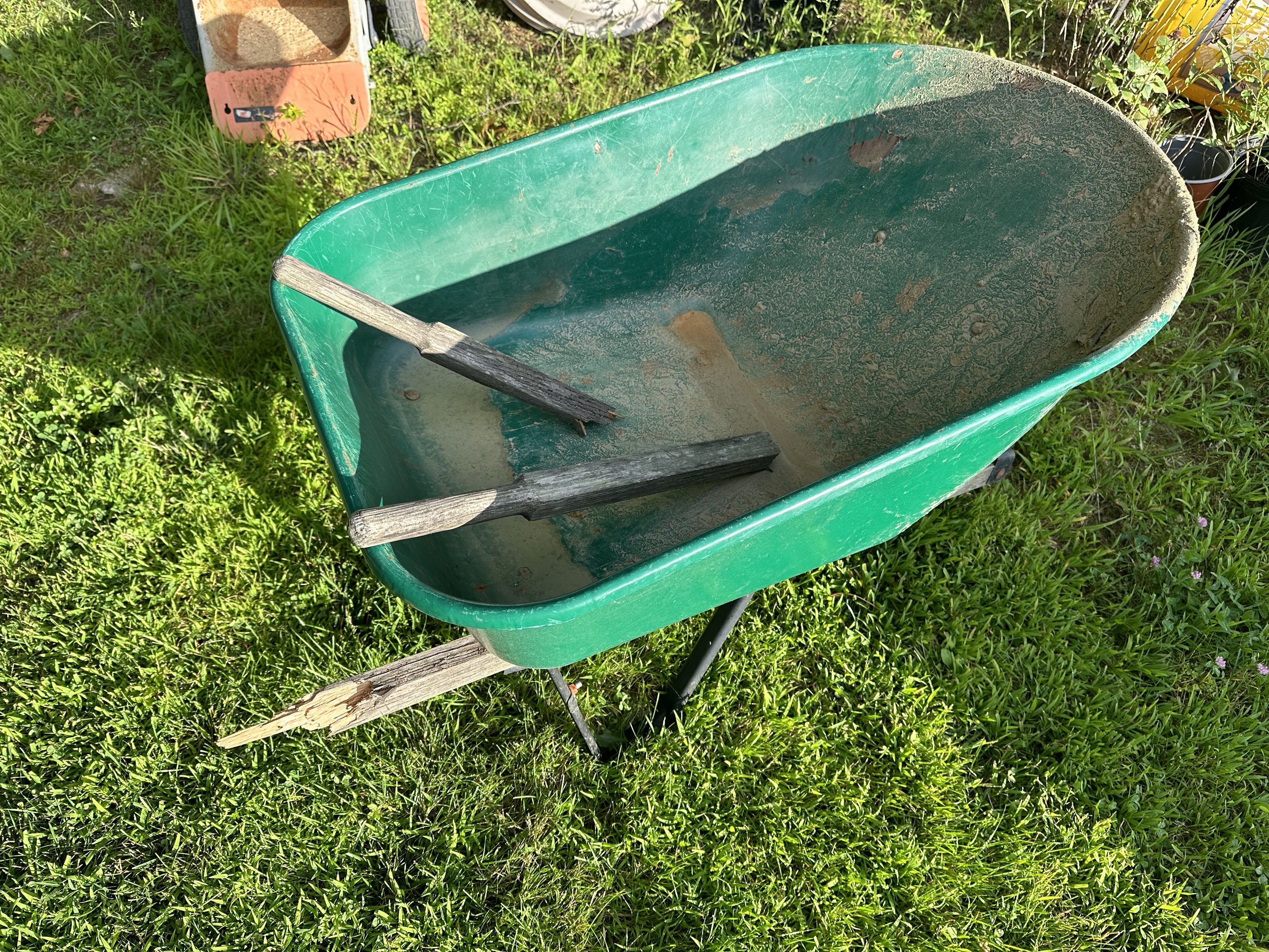 a wheelbarrow whose handles have broken off and are inside the tub