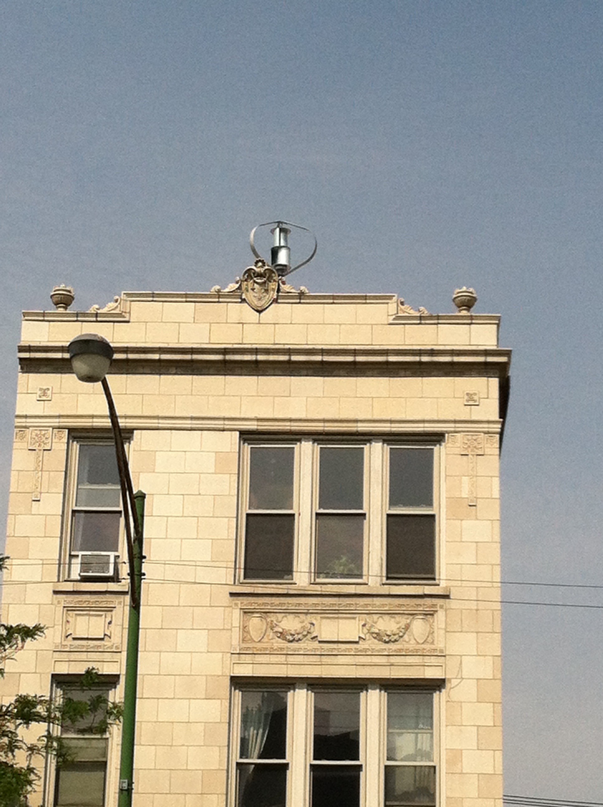 a photo of the top of an apartment building with a vertical-axis wind turbine installed on the roof)