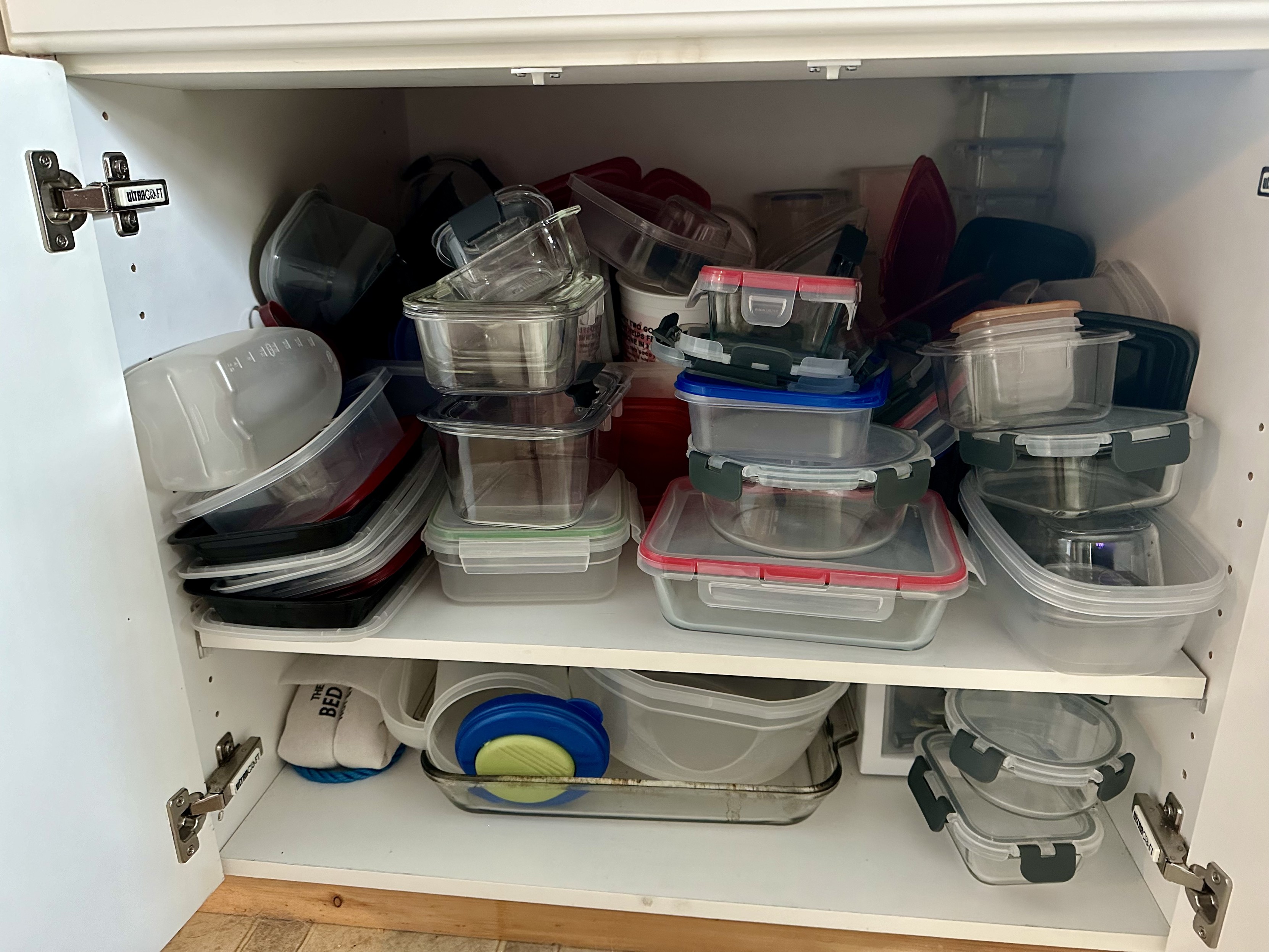 this is a photo of the cupboard in my house where we store food storage containers. it is a mess.