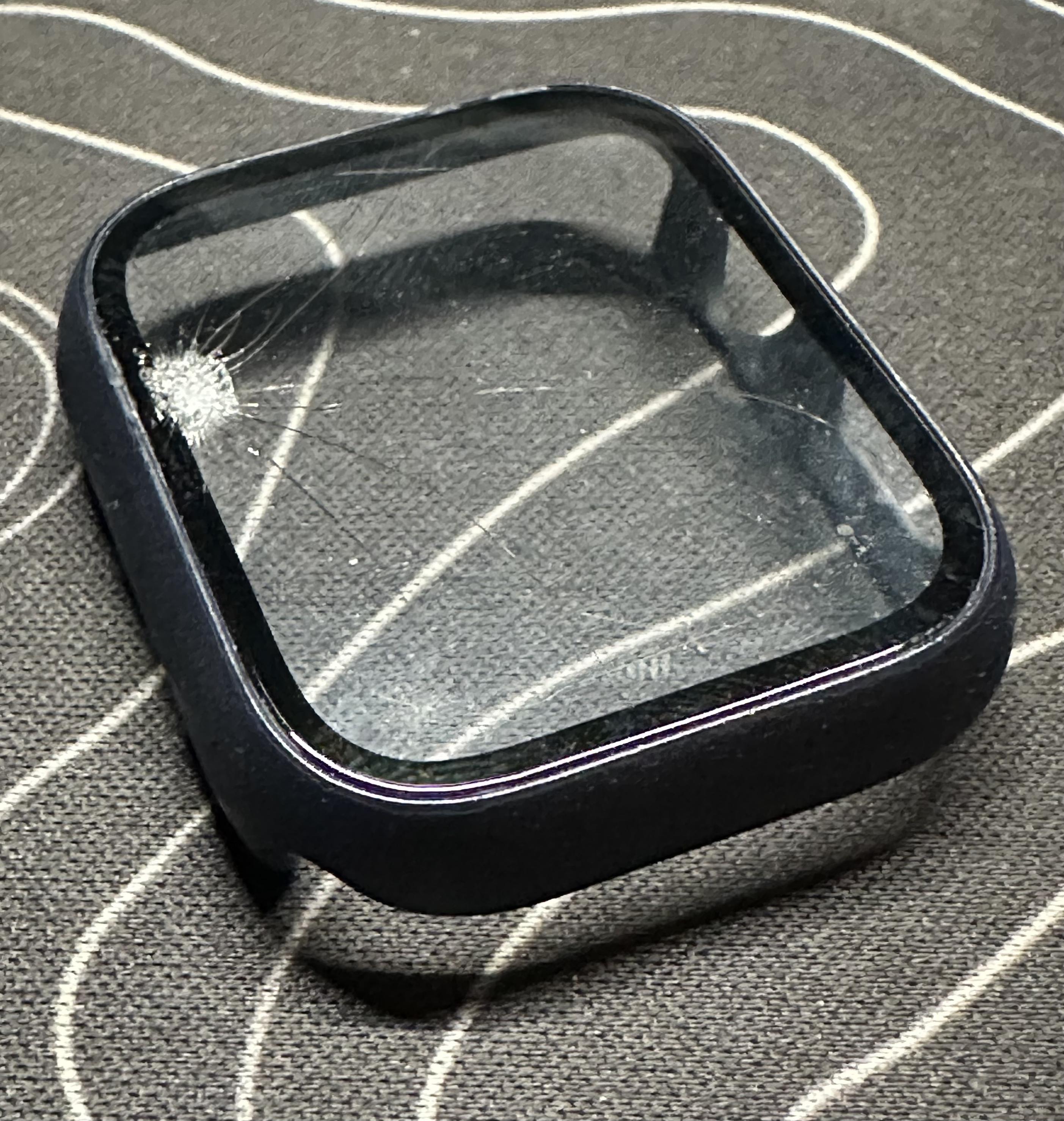 a photo of the guard i just took off of my apple watch with a smashed area and cracks extending out from it