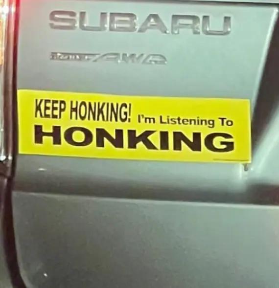 a photo of a bumper sticker on a car which reads “keep honking! i’m listening to HONKING”