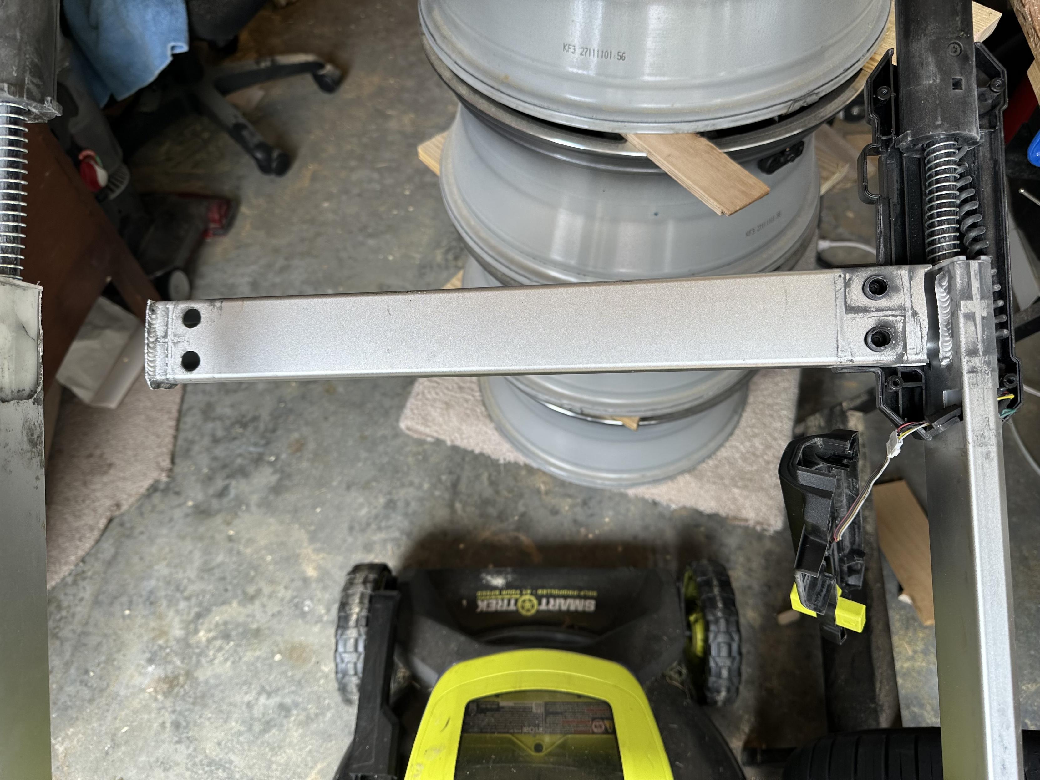 a photo of the aluminum crossbar on the handle of my lawn mower with broken metal around the welds on both sides