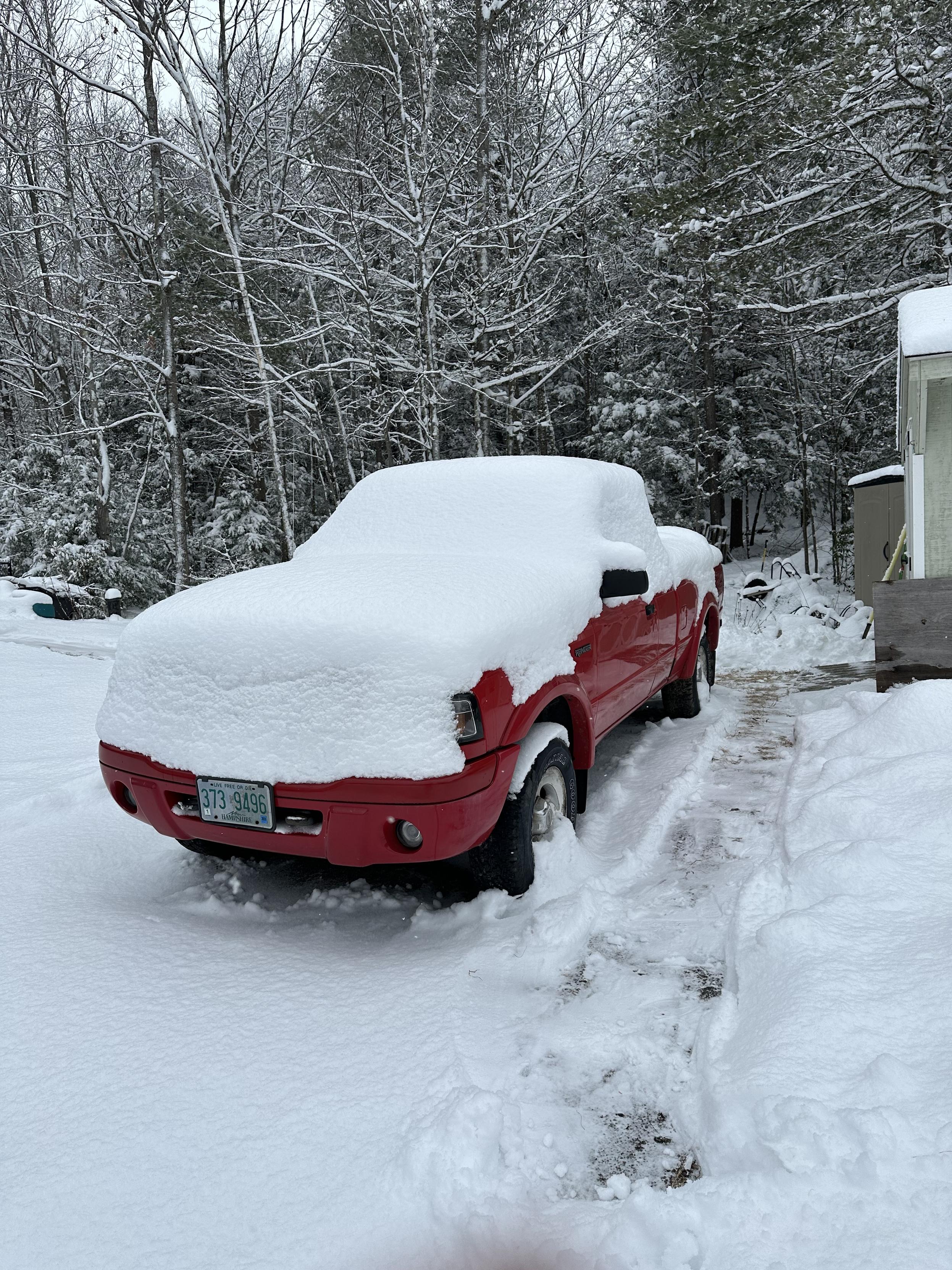 a photo of a red pickup truck covered in snow 
