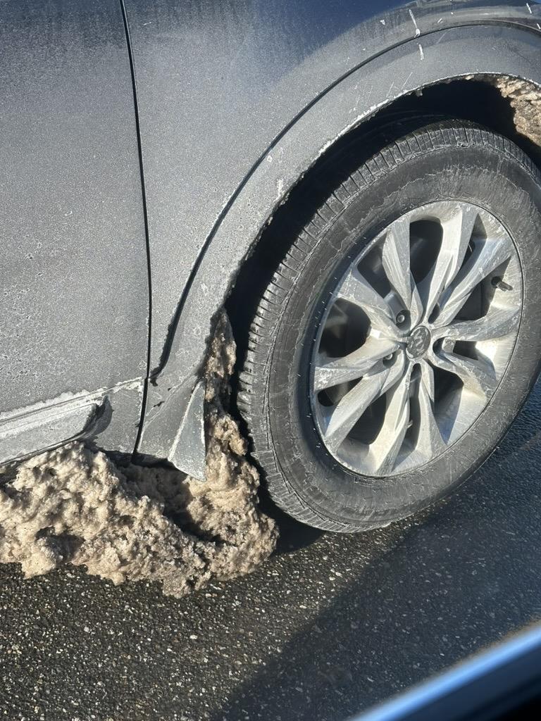 a photo of a massive buildup of frozen slush behind a car wheel