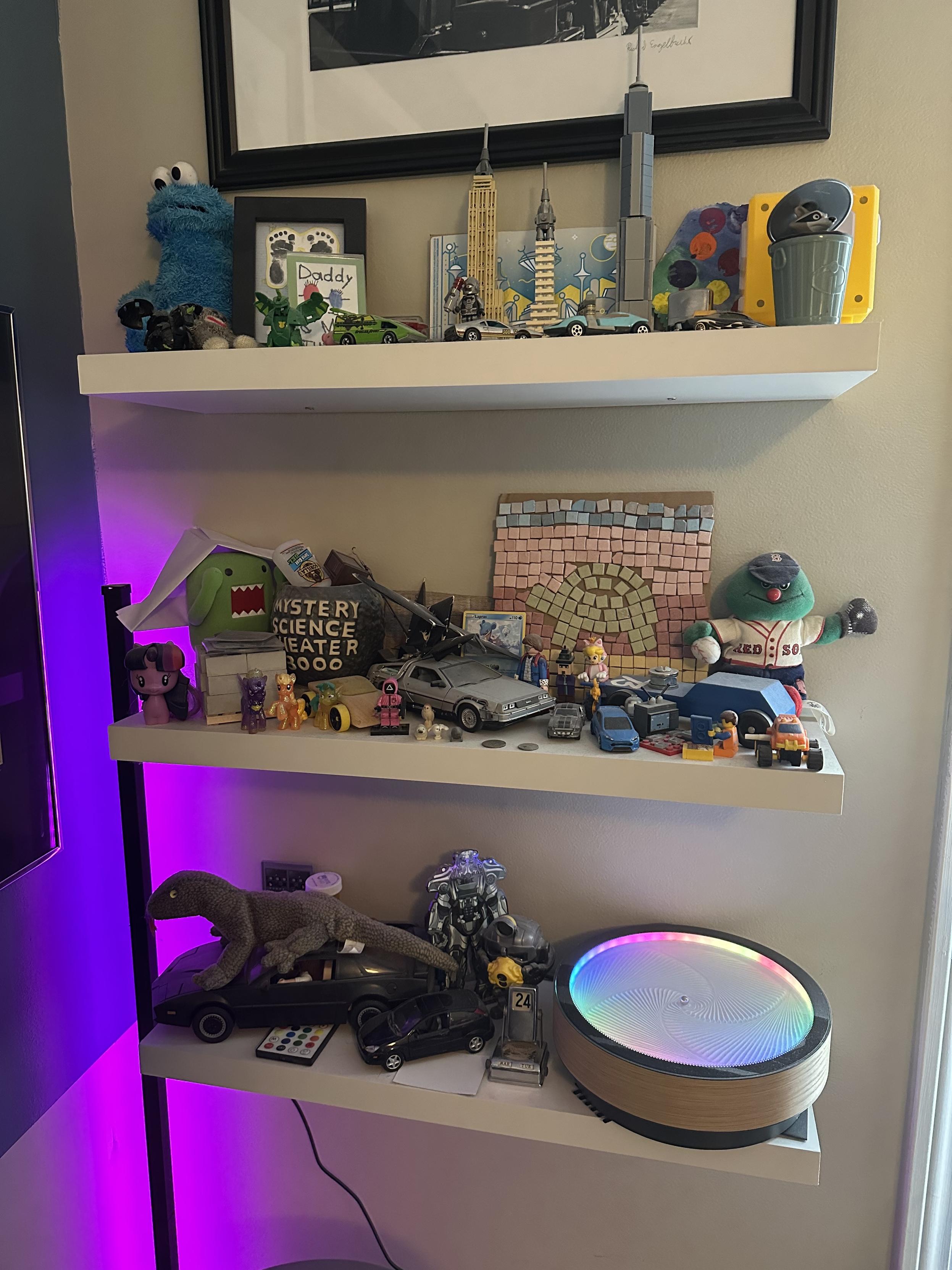 a photo of the shelves next to my desk which contain lots of cars, lego, school art projects, other toys and mementos
