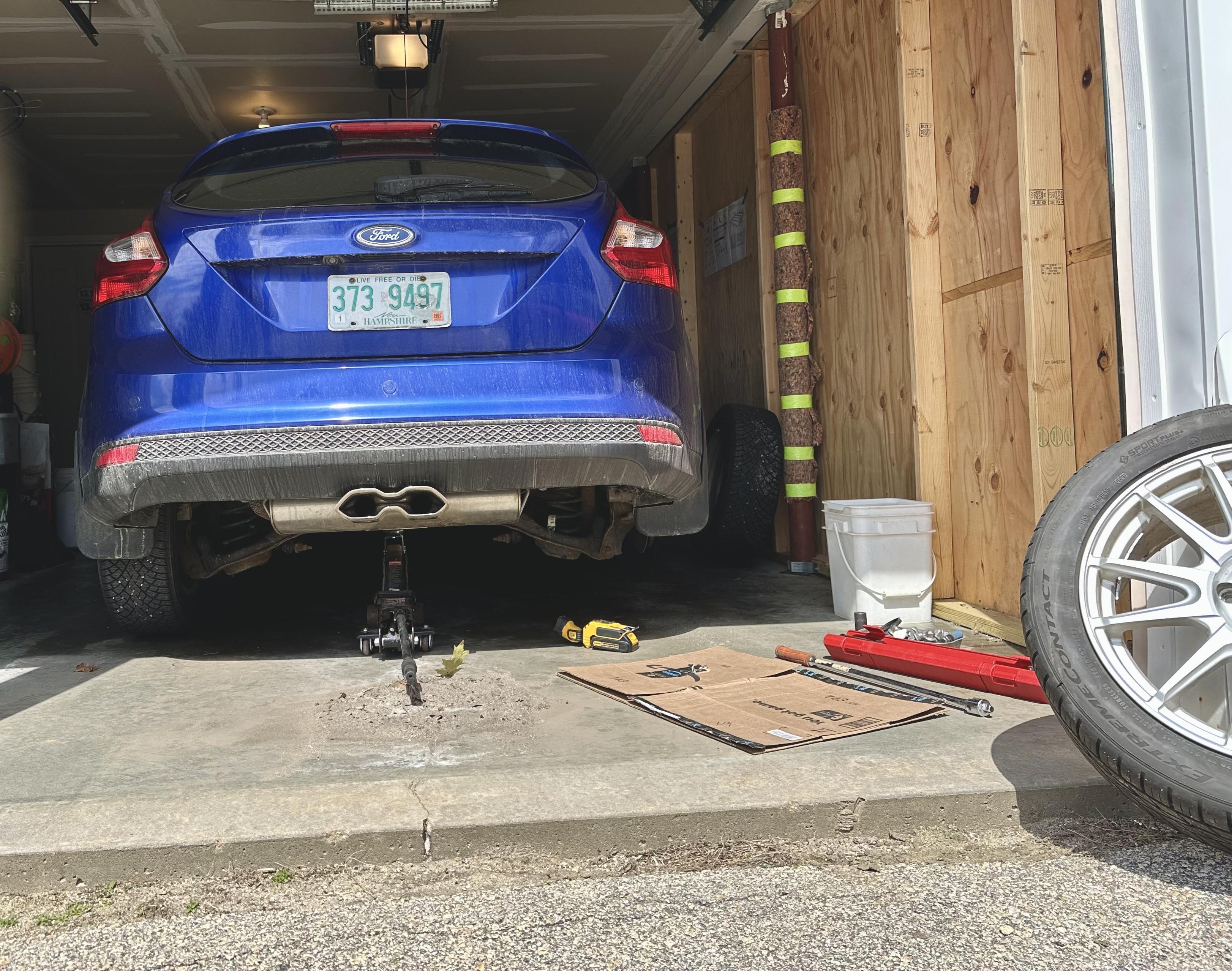 a photo of my focus in the garage with the rear end being held up with a floor jack as i swap my winter and summer wheels