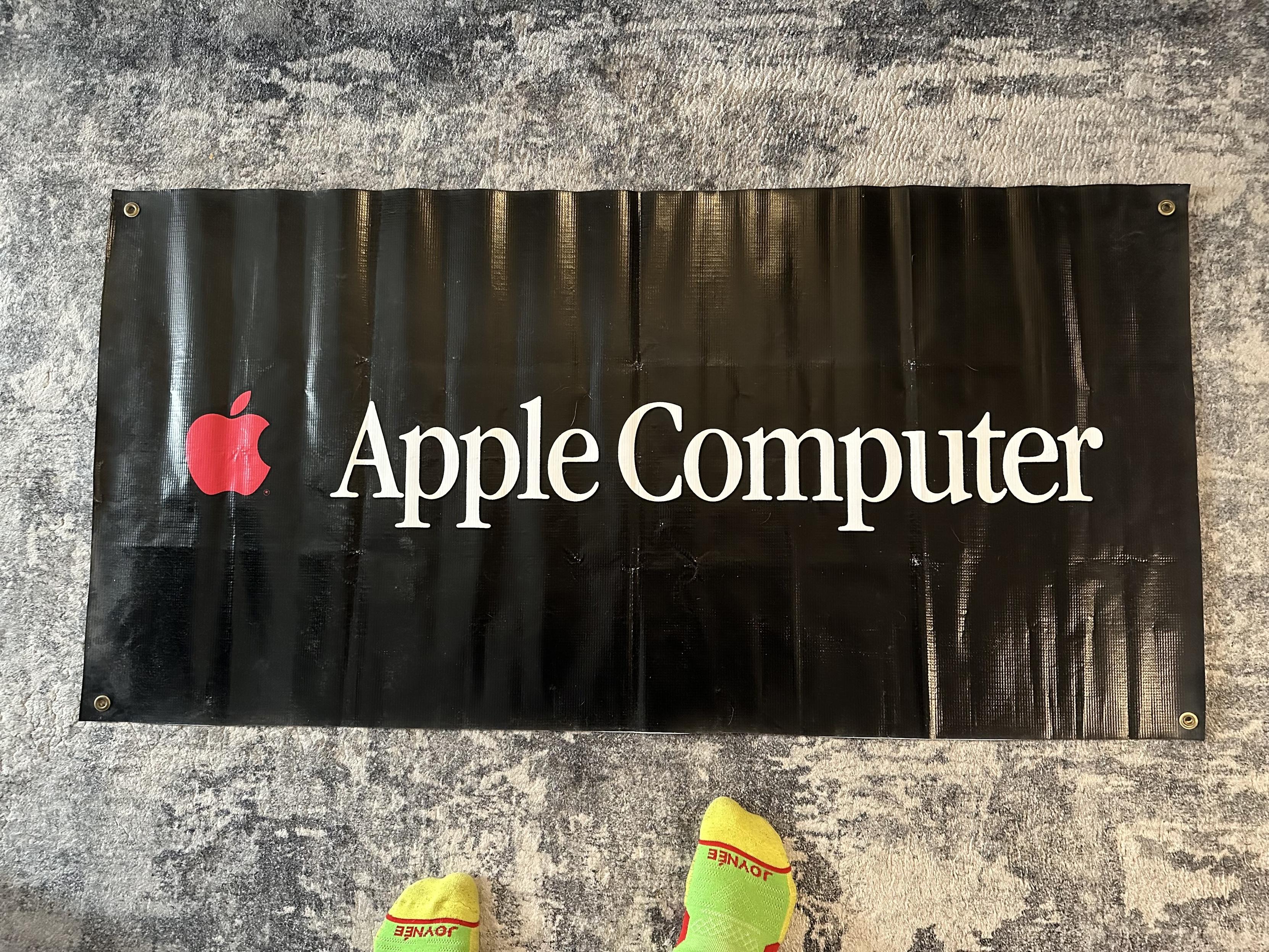 a photo of an Apple Computer banner from the 90s, where the apple logo is solid red, from a time when the computers still had the colorful logo