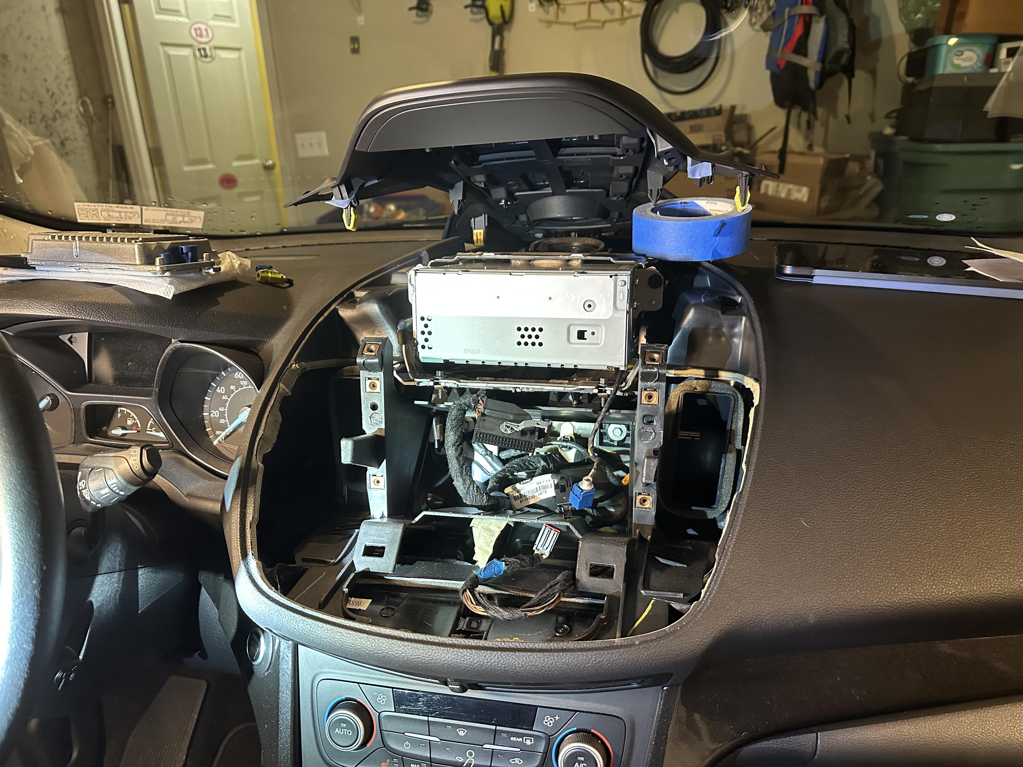 a photo of a 2019 ford escape interior with the center of the dashboard removed and the APIM/screen removed, to replace the APIM.