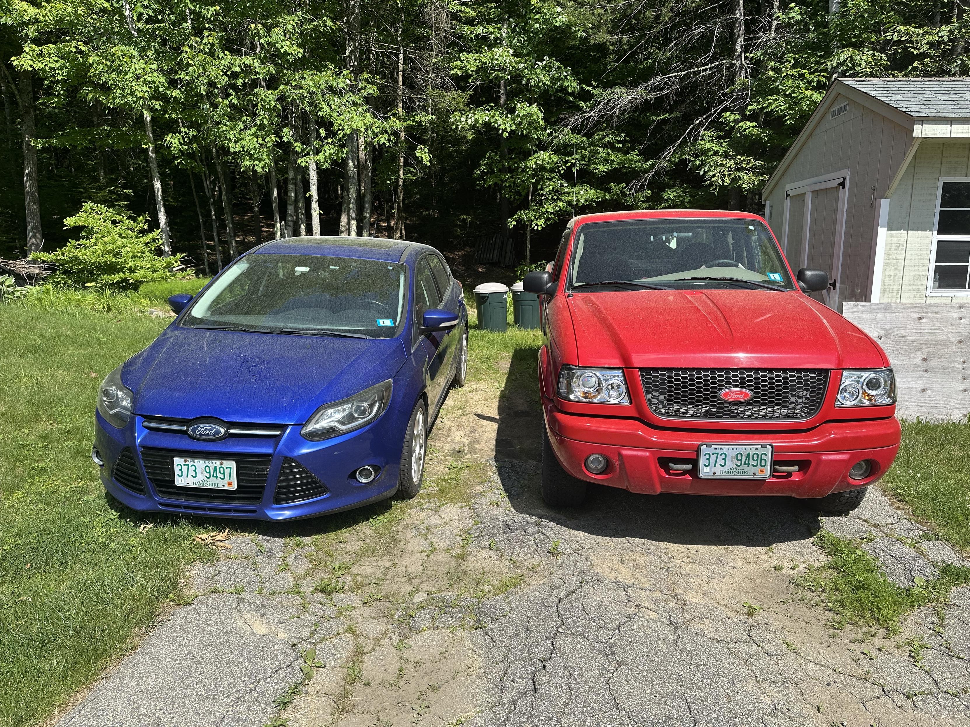 A photo of a blue car and a red pick up truck next to each other, covered in pollen