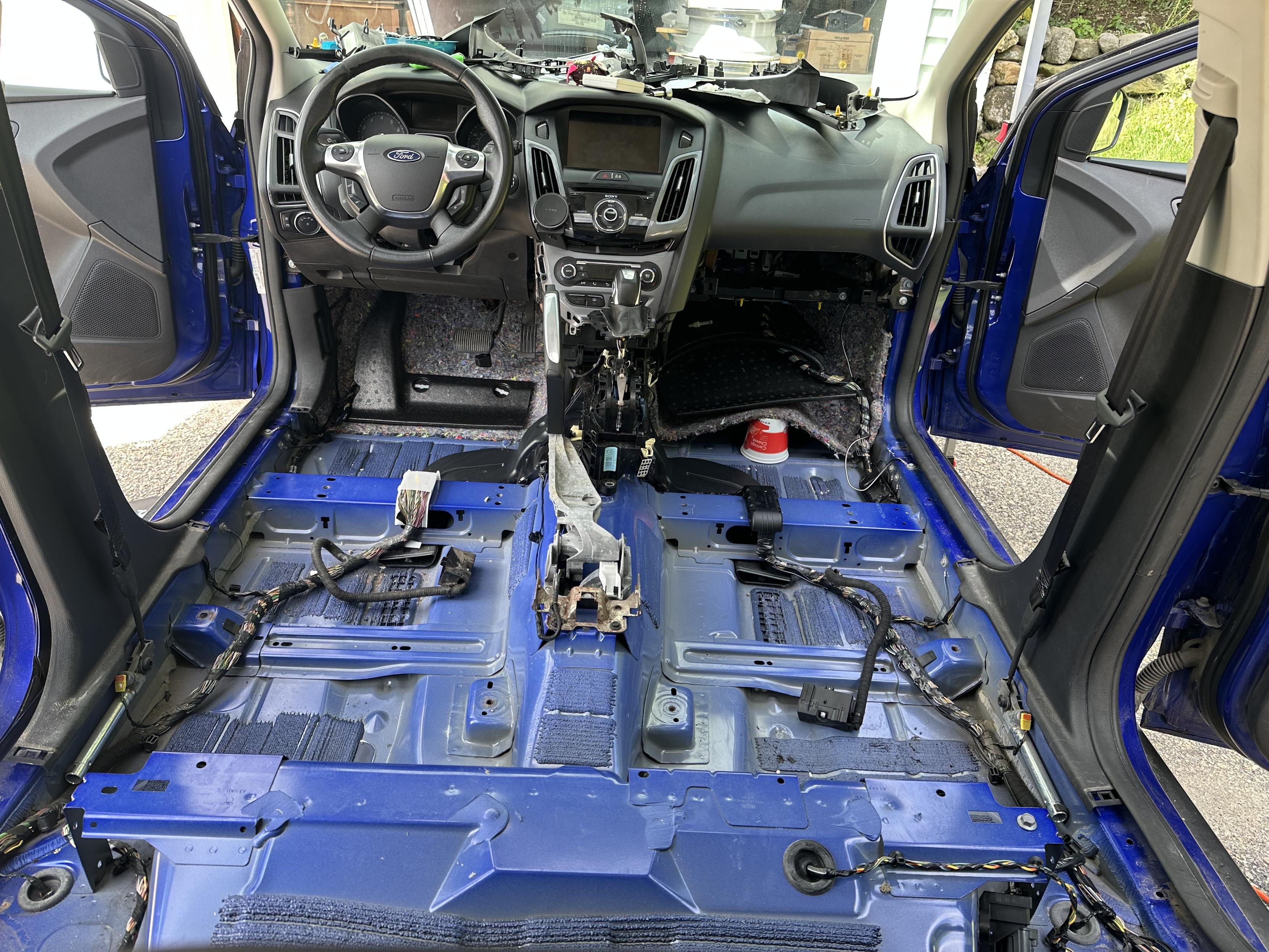 A photo of the interior of my car with the seats, center console, and carpet removed.
